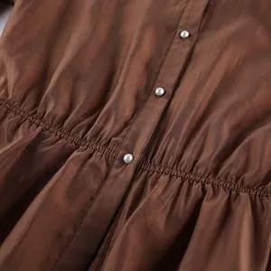 Primer plano de blusa marrón de tencel con botones de perlas y detalle de talle fruncido