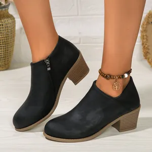Detail shot of black block heel ankle boots with side zipper and tree charm anklet.
