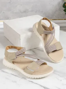 Detail of women's casual wedge sandals with elastic straps and velcro closure in beige.