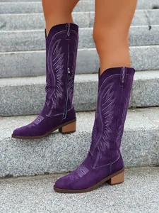 Stylish purple suede mid-calf cowboy boots with white embroidery detail on stone steps.