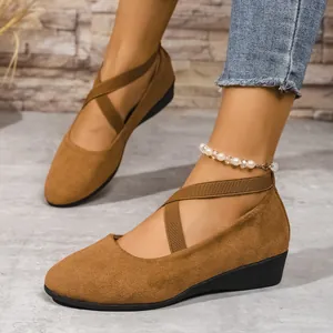 Dettaglio di scarpe marroni in camoscio con zeppa e cinturini elastici incrociati