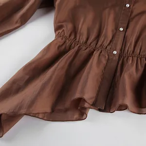 Detalle de una blusa marrón de estilo francés con cintura elástica y botones de perla