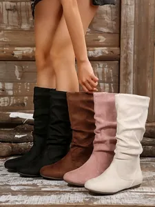 Detailed view of women's slouchy mid-calf boots in multiple colors on wood floor