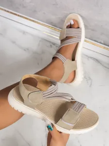 Detail of women's casual sandals featuring beige elastic straps and adjustable Velcro closure.