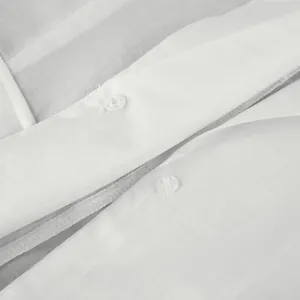 Macro detail of white fabric shirt featuring transparent buttons and fine stitching craftsmanship