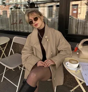 Stylish khaki mid-length trench coat for women featured in a street style cafe setting