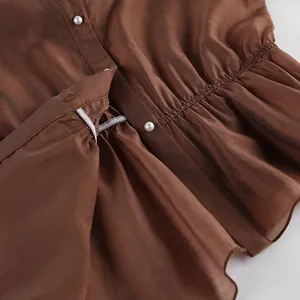 Detalle de una blusa marrón de Tencel con cintura fruncida y botones de perlas