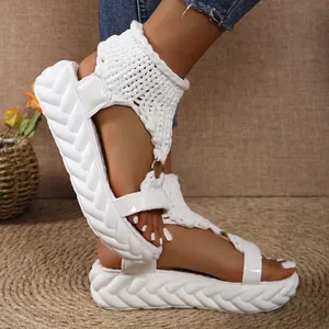 Close-up of white platform sandals featuring knitted uppers and a round buckle detail