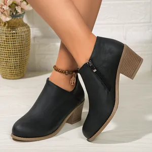 Women's black matte ankle boots with chunky block heels and side zippers on feet