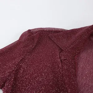 Close-up of wine red glittery fabric on a long sleeve shirt collar and shoulder area.