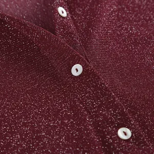 Detail shot of a shimmering maroon shirt featuring elegant white pearl-like buttons.