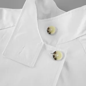 Detailed macro view of white trench coat featuring elegant amber buttons and fabric