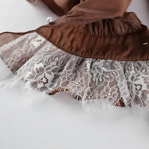 Detalle del puño de una camisa de Tencel marrón con encaje blanco y botón de perla