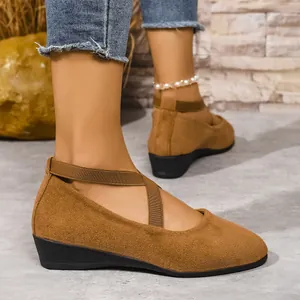 Primo piano di scarpe con zeppa in camoscio marrone e cinturini elastici incrociati