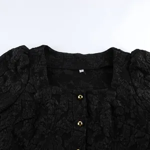 Dettaglio di camicetta in jacquard nero con scollo quadrato e bottoni dorati eleganti