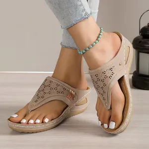 Close-up of beige wedge thong sandals featuring intricate laser-cut hollow designs and stitching