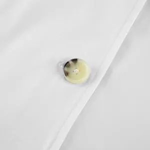 Macro view of a marbled resin button and fine stitching on a white trench coat detail