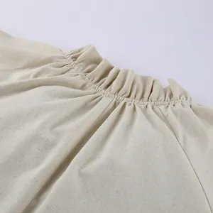 Close-up detail of the elegant ruffled neckline on a natural beige French linen dress