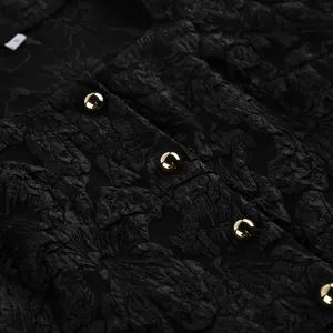 Dettaglio del tessuto jacquard nero con eleganti bottoni dorati in primo piano.