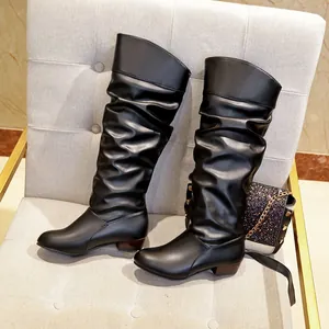 Side detail of black slouchy mid-calf boots with pleated shaft and low block heel