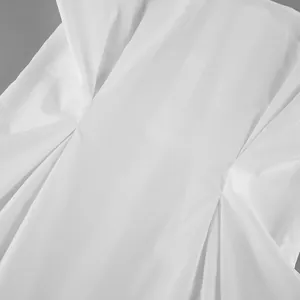 Close-up macro detail showing the elegant pleated waist design of a white cotton shirt