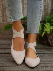 Detalle de bailarinas de ante beige con punta afilada y elegantes correas elásticas cruzadas