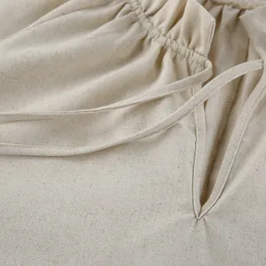 Detail shot of French style beige linen dress with V-neckline and tie design.
