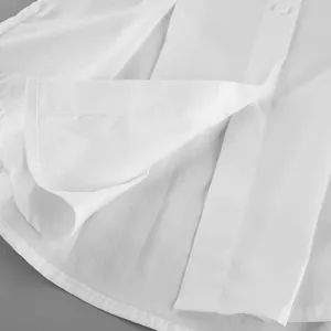 Close-up detail of pleated white pure cotton shirt showing fabric texture and button