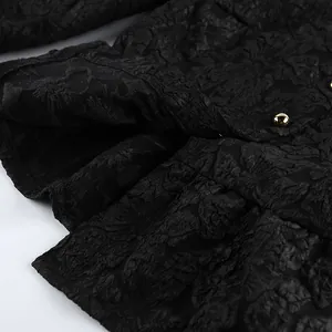 Dettaglio del tessuto jacquard nero con trama floreale e bottoni dorati eleganti