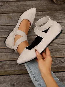 Detalle de bailarinas de punta en ante beige con correas elásticas cruzadas de cerca