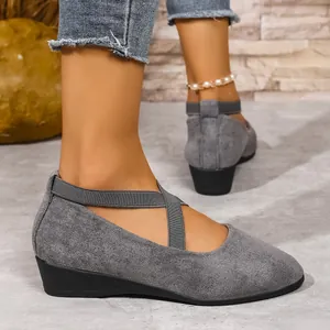 Dettaglio di scarpe con zeppa in camoscio grigio con cinturini incrociati elastici.