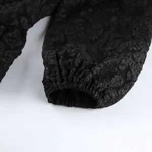 Vista macro dettagliata del tessuto jacquard floreale nero e polsino elastico della camicetta