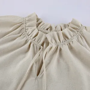Macro view of ruffled high neck and V-neckline with elegant ties on beige linen dress