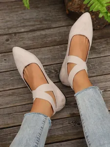 Detalle de bailarinas de ante beige con tiras elásticas cruzadas en suelo de madera
