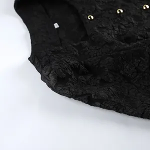 Dettaglio del tessuto jacquard nero testurizzato con eleganti bottoni sferici dorati