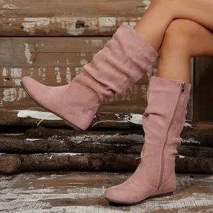 Detail view of pink suede slouchy mid-calf boots with side zipper and flat sole