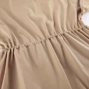Détail en gros plan de la taille réglable à cordon sur un long trench-coat kaki