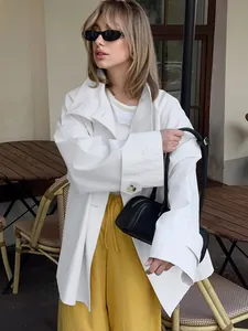 Stylish white oversized trench coat paired with yellow pants in a chic street style setting