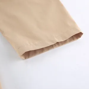 Gros plan de l'ourlet d'un trench-coat kaki montrant les coutures et la texture