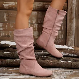 Detailed view of pink suede slouchy mid-calf boots with side zipper on logs