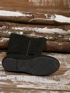Close-up view of black suede slouchy boot sole with textured anti-slip grip pattern