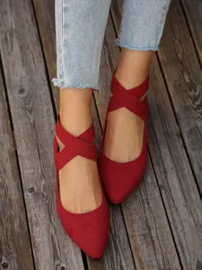 Detalle de bailarinas de ante rojo con punta fina y correas elásticas cruzadas.