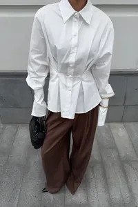 Elegant white cotton shirt detail featuring pleated waist design and long cuffs