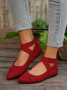 Vista detallada de bailarinas de ante rojo con correas elásticas cruzadas.
