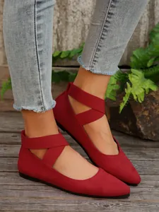 Detalle de elegantes bailarinas de ante rojo con correas cruzadas en el tobillo