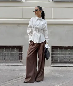 Street style detailed view of the white long-sleeve cotton shirt with pleated waist design