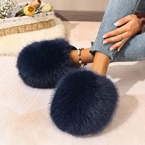 Close-up of navy blue fluffy faux fur slippers for women in a cozy home setting