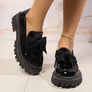 Nahaufnahme der schwarzen Lackleder-Plateau-Loafers mit einer schicken großen Schleife