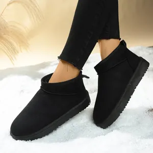 Close-up of black women's snow boots with warm fur lining on a snowy surface.
