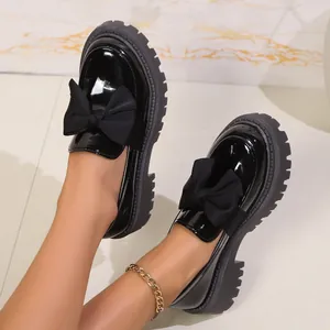 Nahaufnahme von schwarzen Lackleder-Plateau-Loafers mit dekorativem Schleifendetail